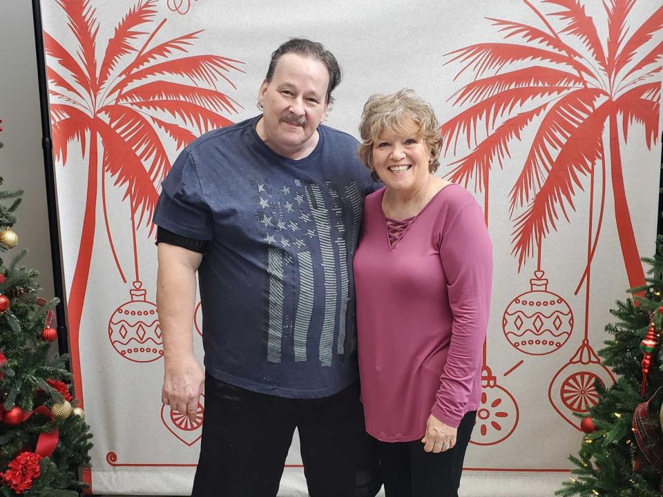 A couple posing for a photo in front of holiday decorations.