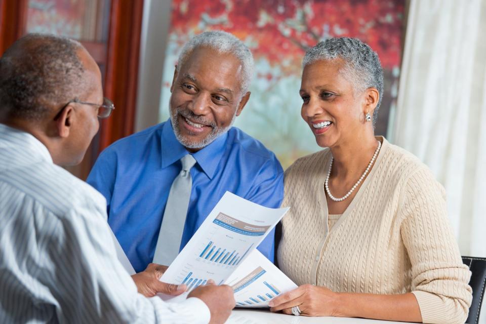 A married couple looking at financial paperwork with an advisor. 