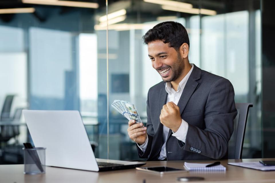 Someone smiling while holding cash.