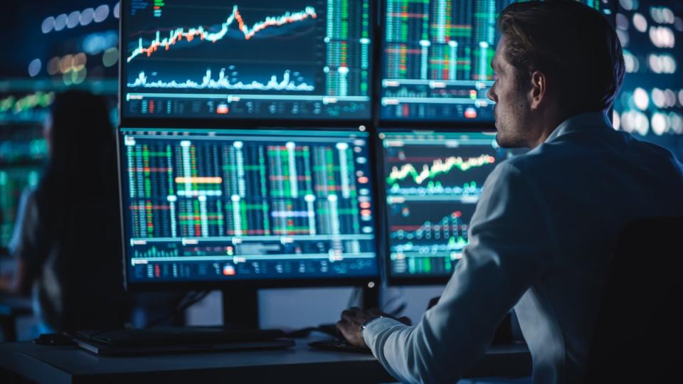 Trader working at desk with multiple trading screens.