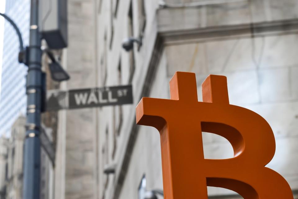 Artist's rendering of Bitcoin logo in front of the Wall Street street sign.