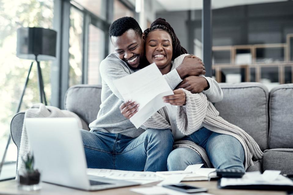 Two smiling people embracing while looking at documents.