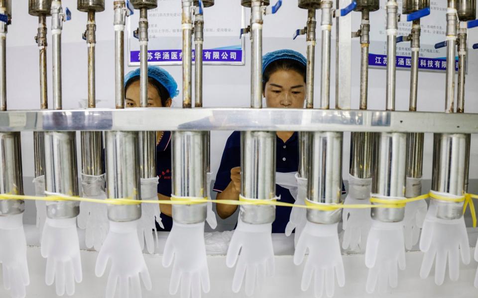 Workers on a PVC glove production line at a factory in Sihong, after China's industrial output slumped in August