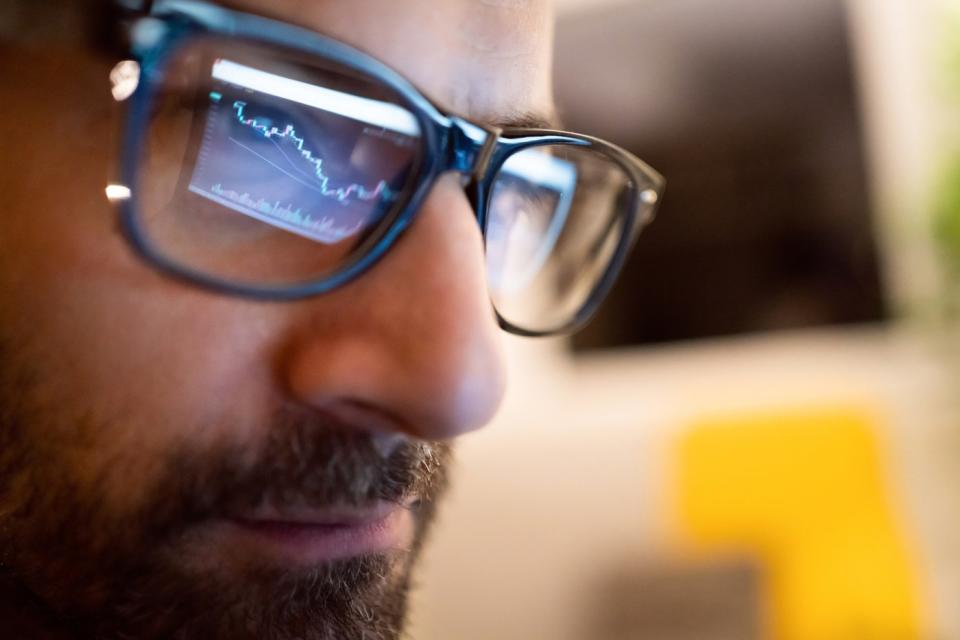 A stock chart from a computer monitor being reflected on the eyeglasses of a professional money manager. 