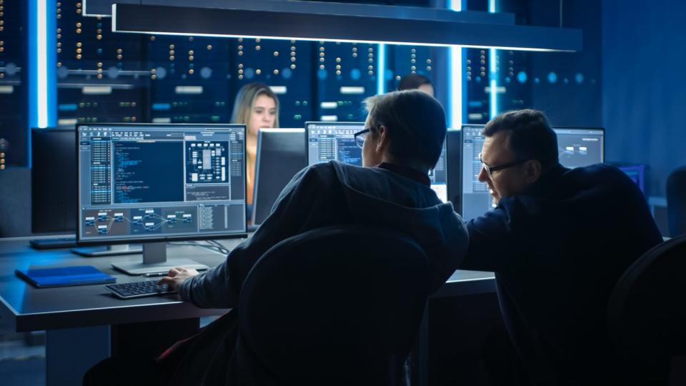 Developers looking at lines of AI code on a computer screen.