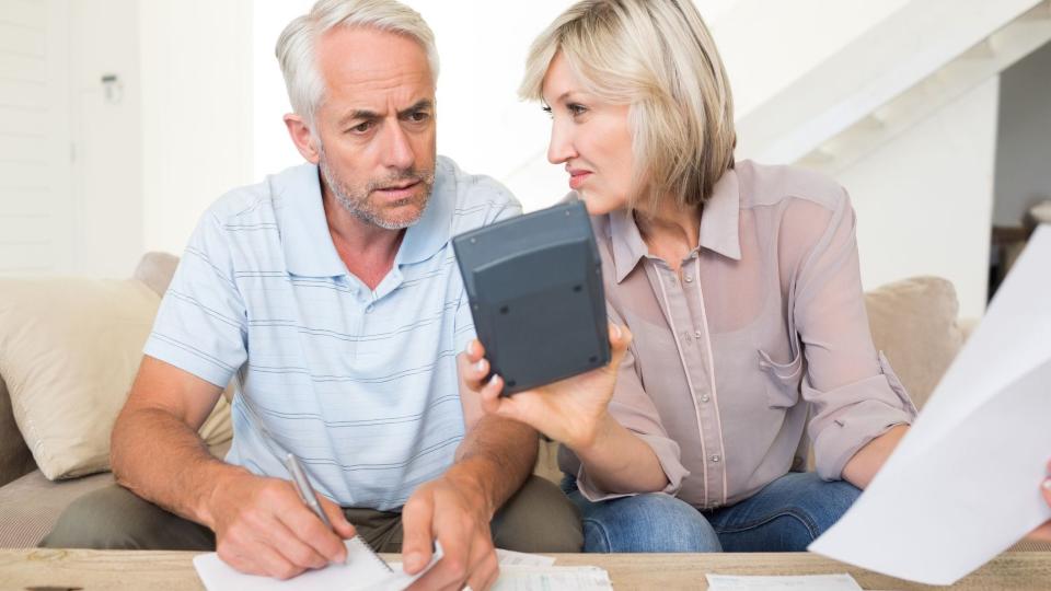 A couple does some math on a calculator to determine if they should switch to Roth contributions or complete a Roth conversion.