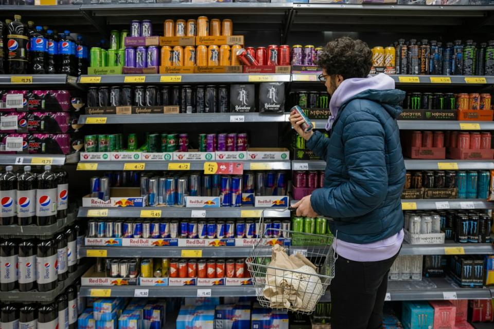 Person at a grocery store looking for an energy drink.