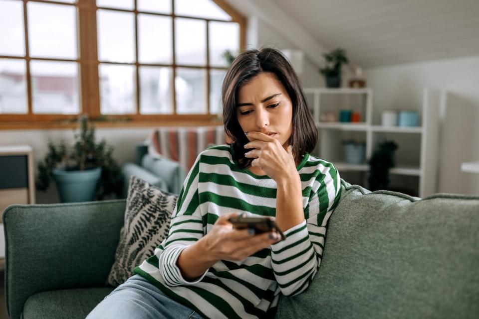 Person sitting on a couch, looking at their phone.