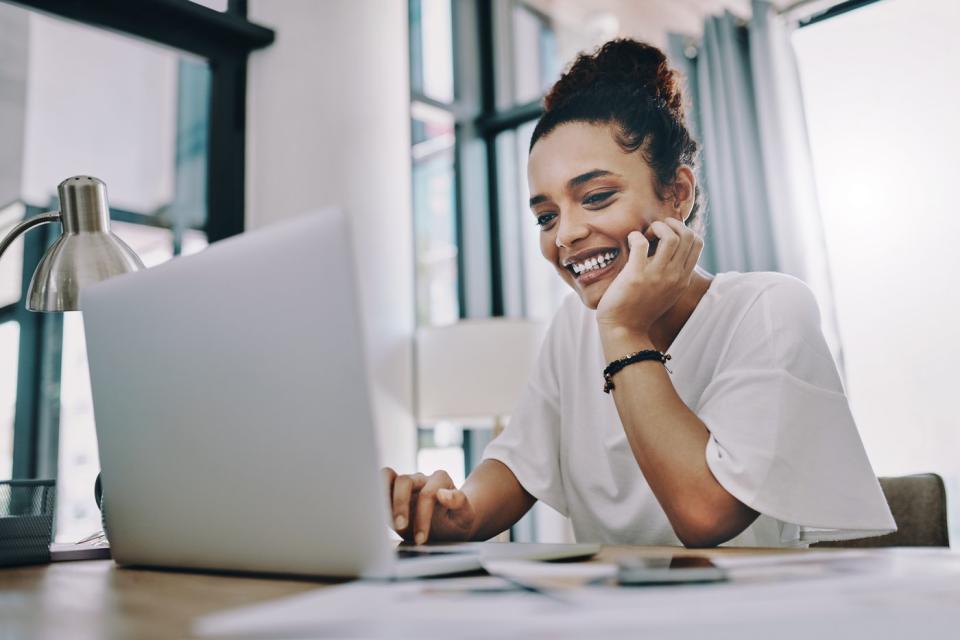 An investor smiles while looking at a laptop.