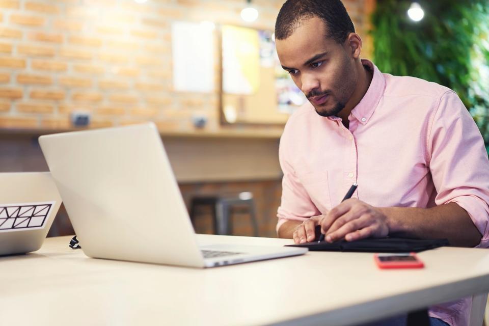 An investor studies something on a laptop at home.