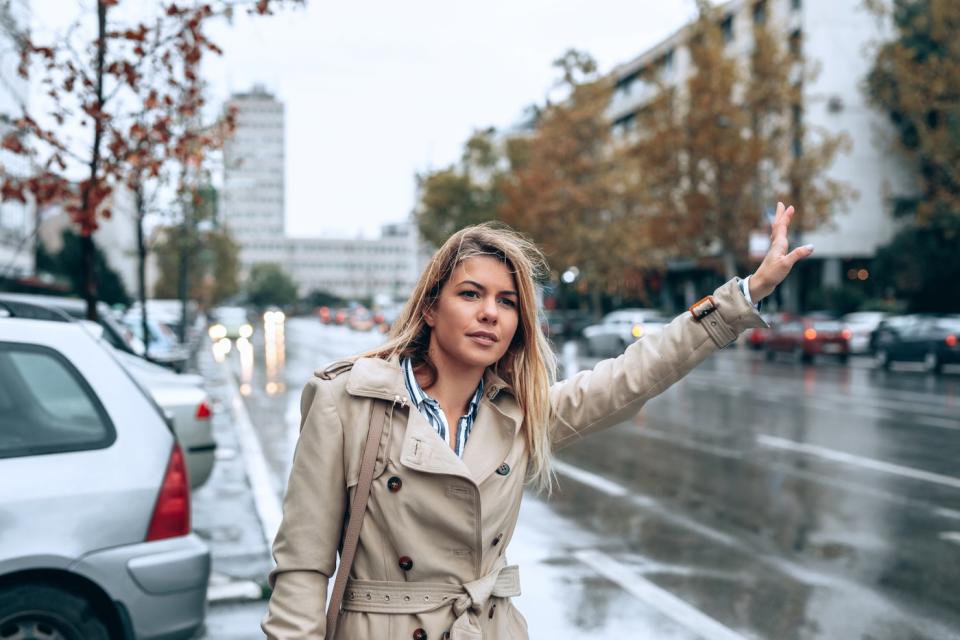 Person hailing a taxi on a busy city street.