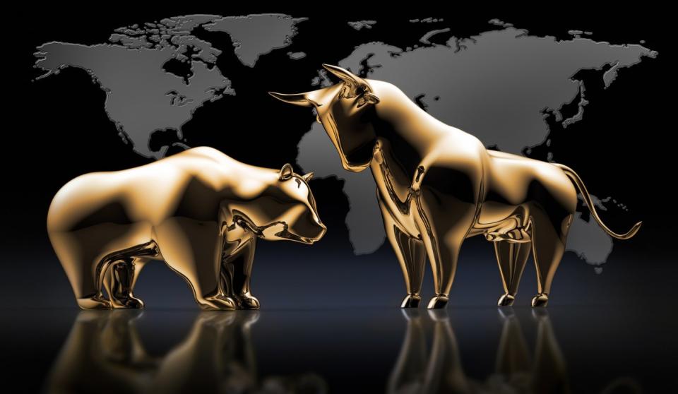 Golden bull and bear statues in front of a global map.