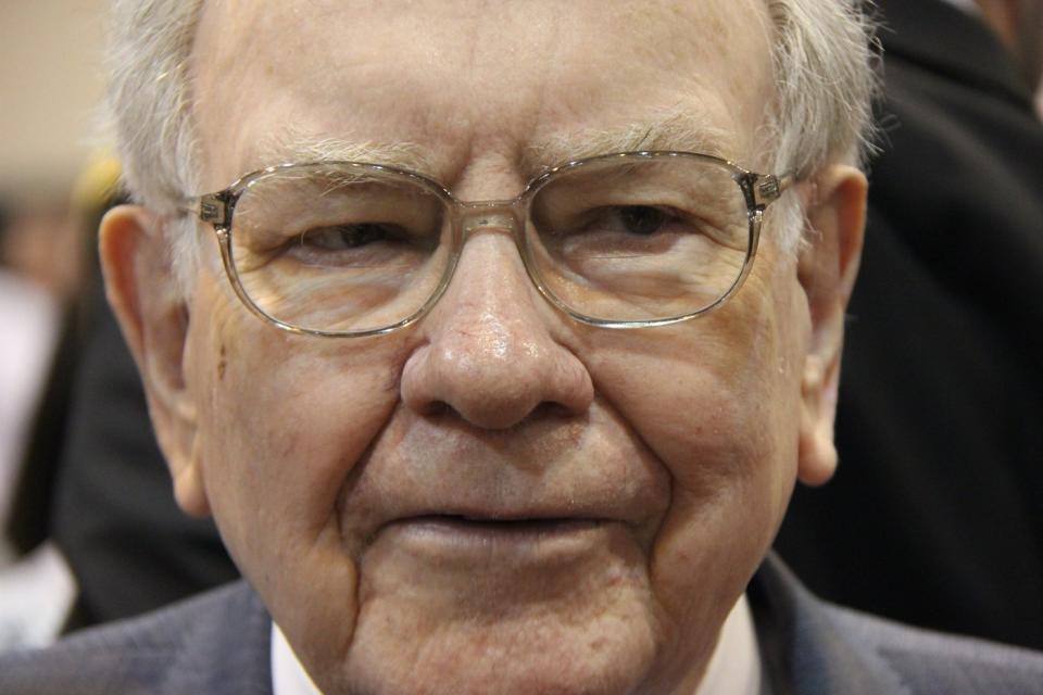 A pensive Warren Buffett surrounded by people at Berkshire Hathaway's annual shareholder meeting.