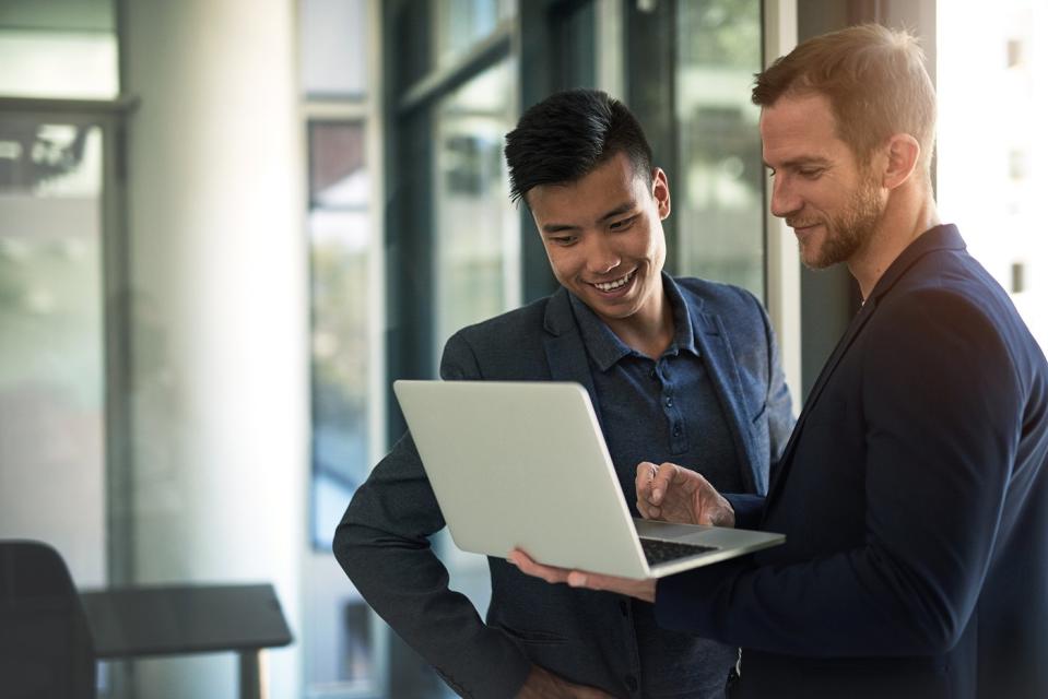 Two investors look at something on a laptop in an office.