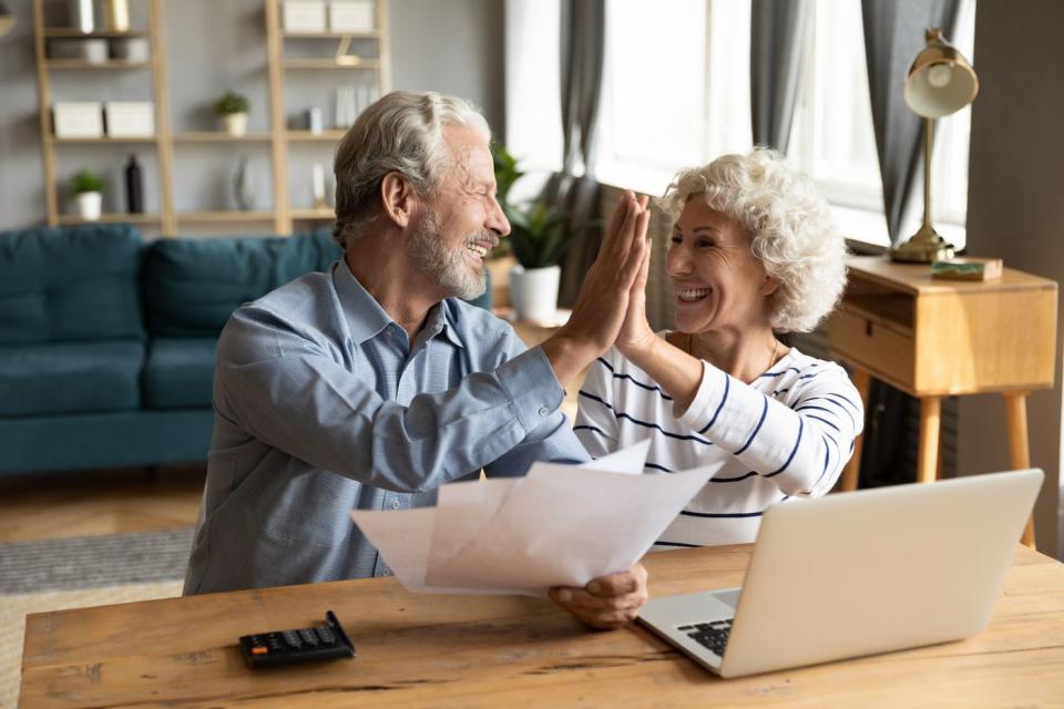 Two people high-fiving in front of laptop.