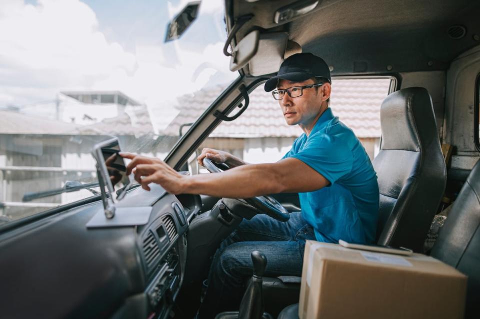 A person tapping a screen while sitting in a delivery truck.