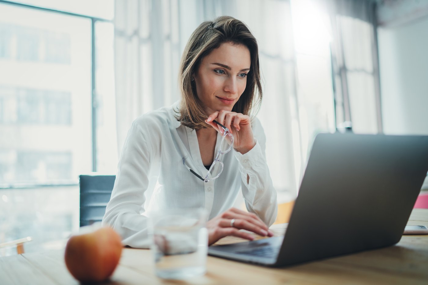 An investor in an office looks at something on a laptop.