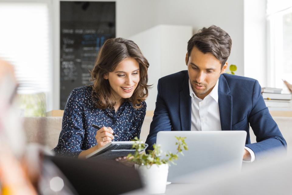 Two investors in an office study something on a laptop.