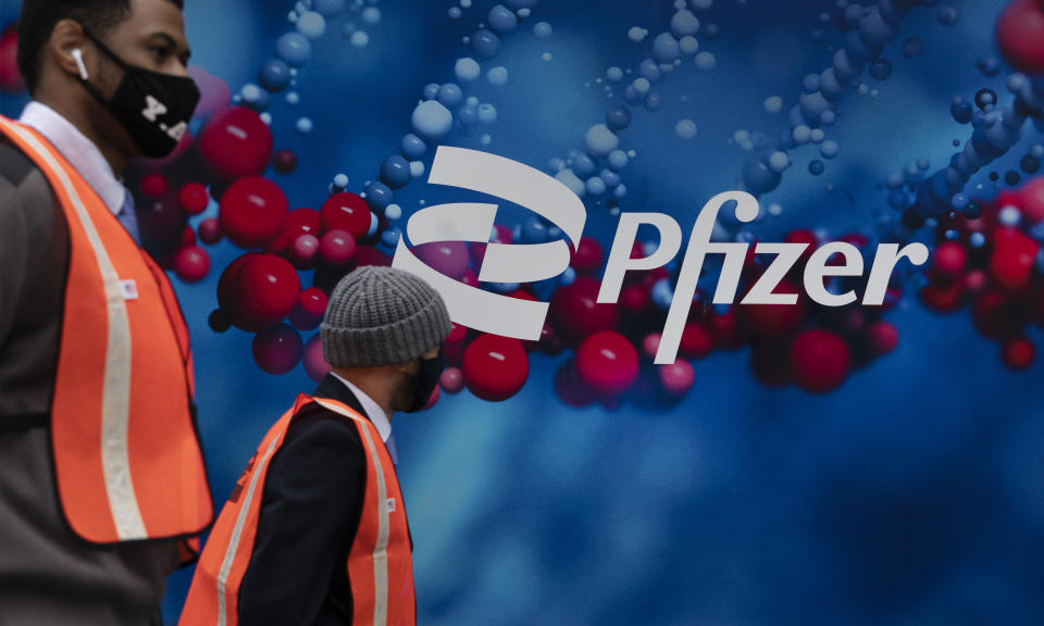 Men walk by Pfizer headquarters, Friday, Feb. 5, 2021 in New York. (AP Photo/Mark Lennihan)