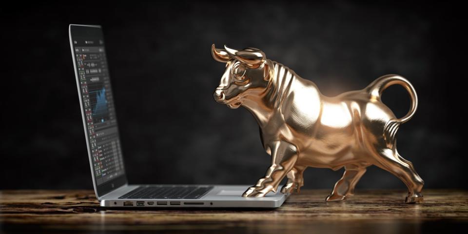 A sculpture of a golden bull standing on a laptop computer.