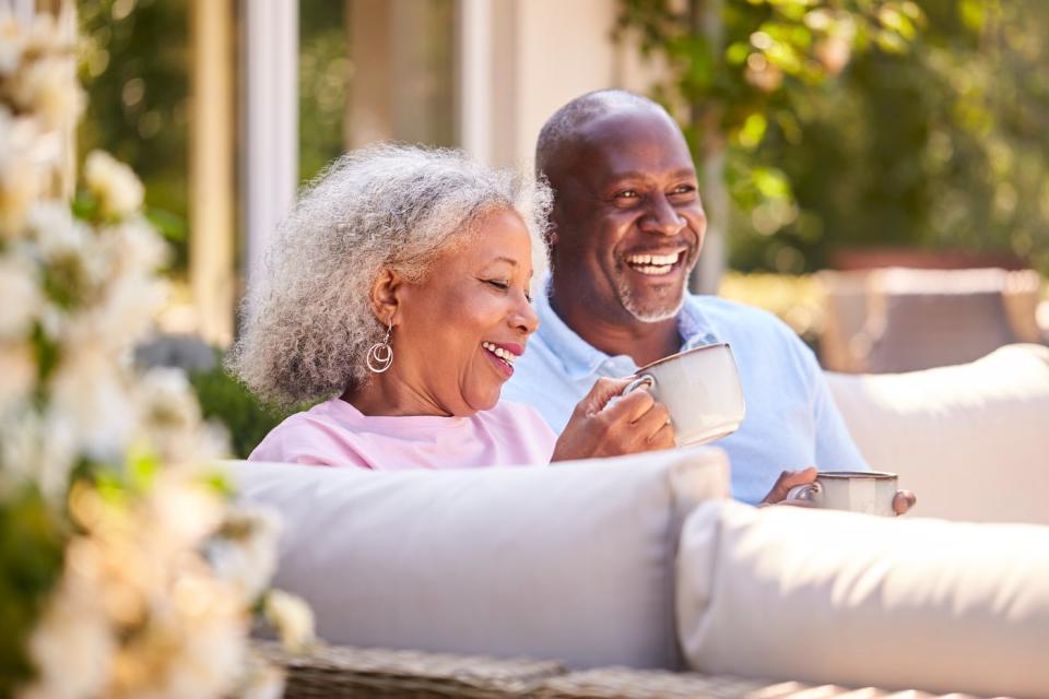 A retired couple sitting on their patio drinking coffee.