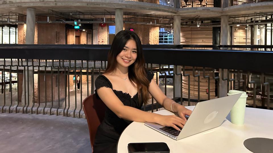 A young woman using her laptop in a university building.